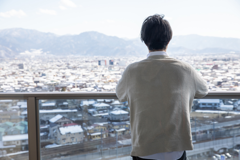 景色を眺める男性の後ろ姿の画像