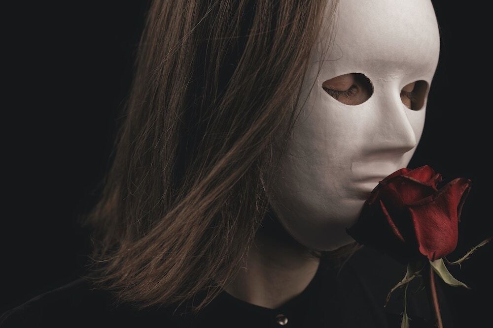 仮面をつけて薔薇を持った女性の画像