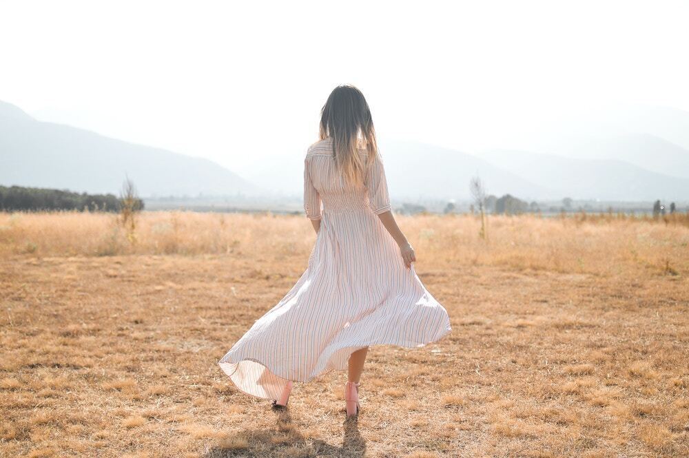 草原で歩く女性の後ろ姿の画像